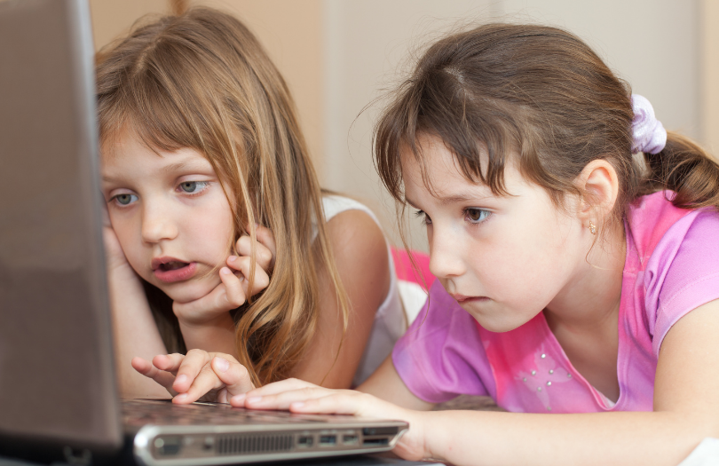 Two young girls sharing a laptop