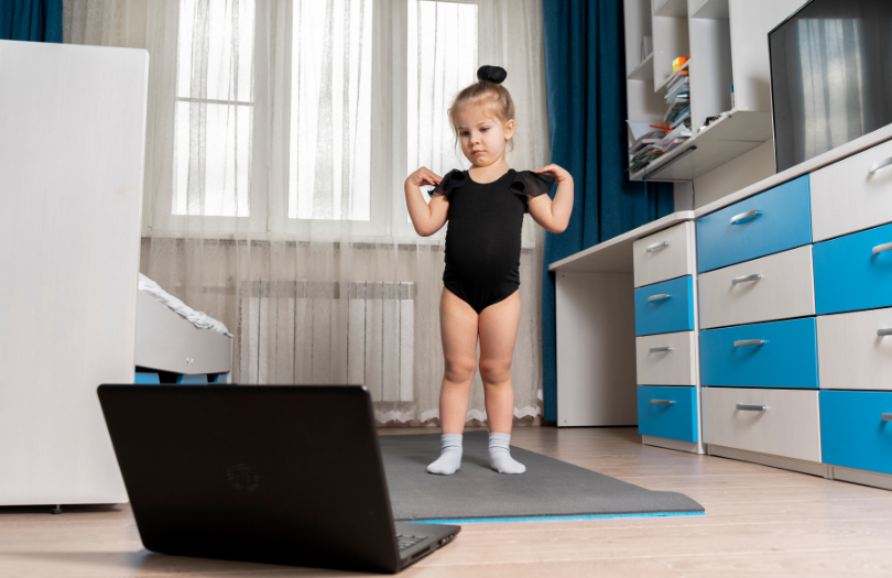 Little girl in leotard in front of laptop