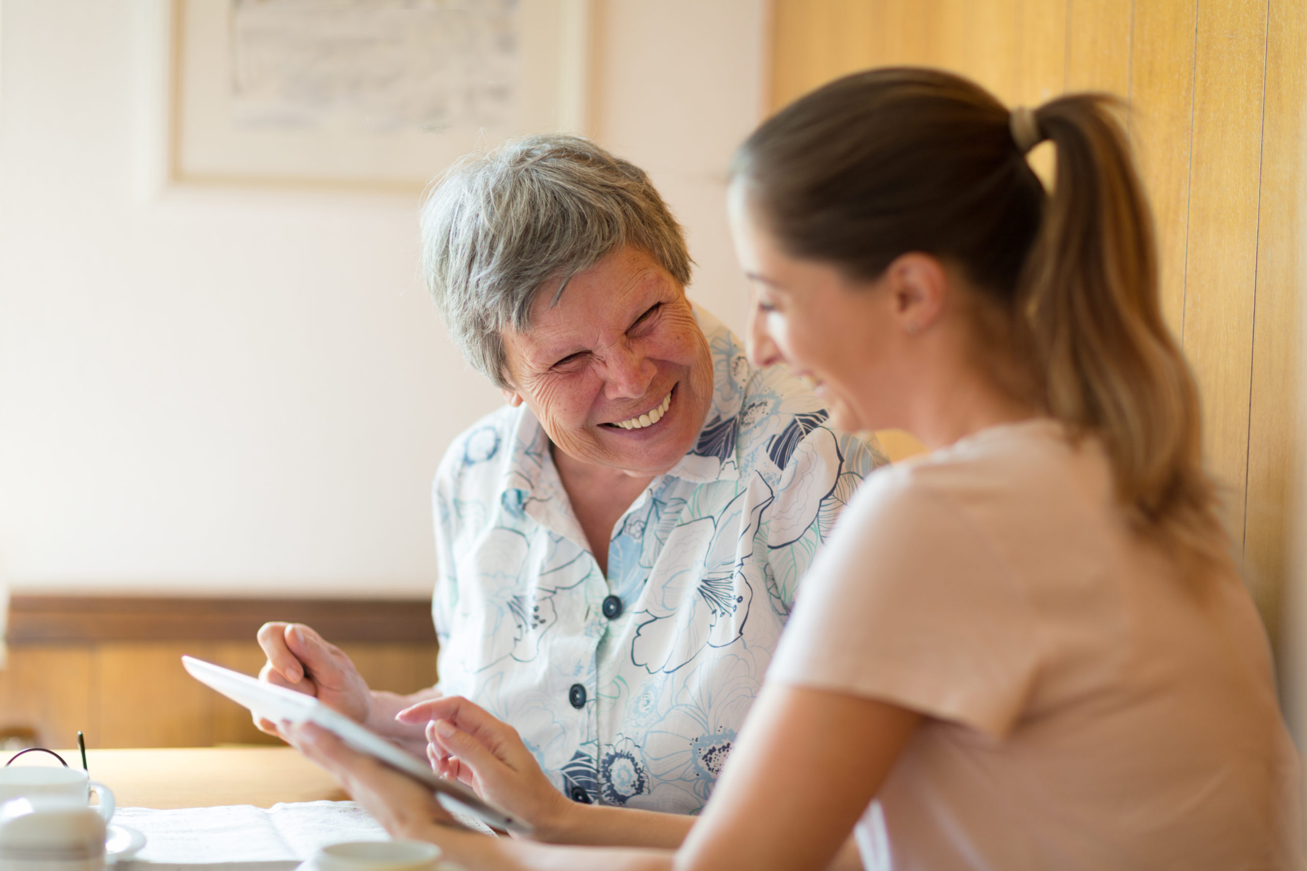 Young woman shows older woman how to use a tablet