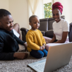 Young black family look at laptop on the floor