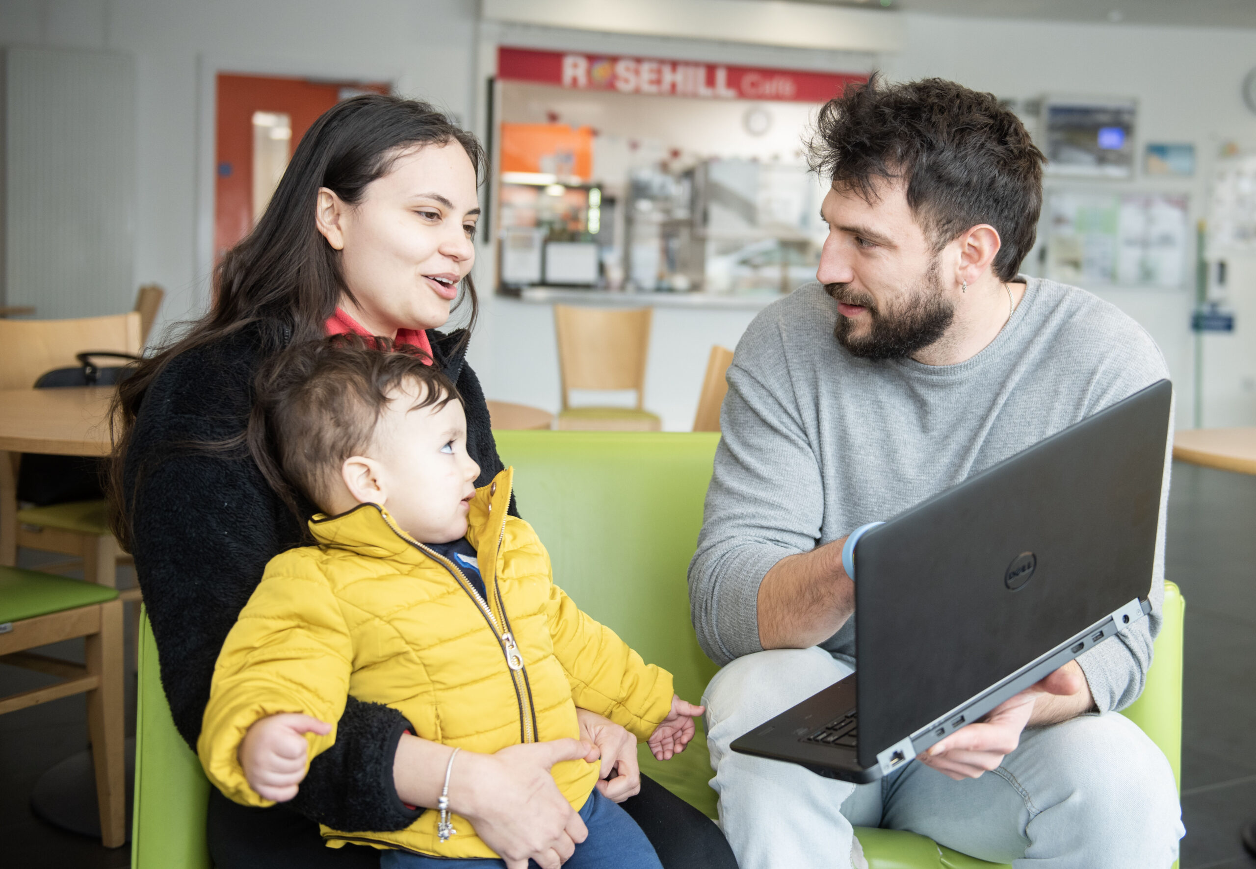 Woman looking at laptop held by man with child on her lap